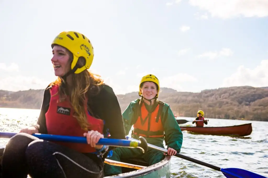 Two Scouts canoeing with another Scout in the background